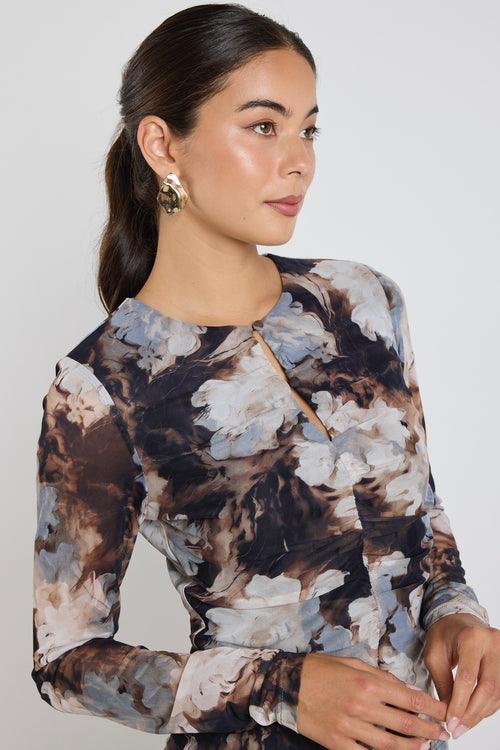 model wears a brown and blue mesh floral top with a black maxi skirt