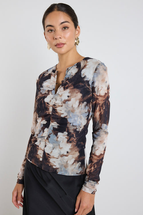 model wears a brown and blue mesh floral top with a black maxi skirt