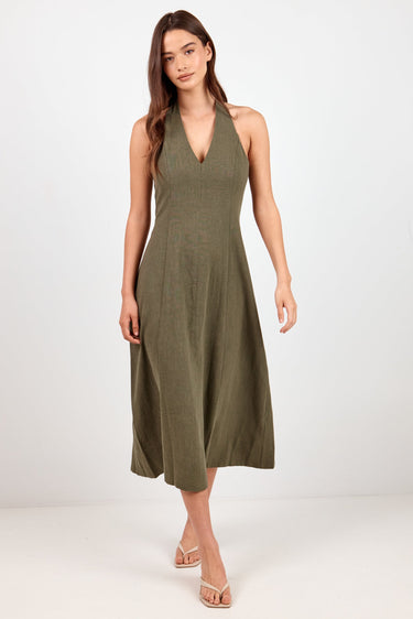 A woman modeling a sleeveless olive green midi dress with a V-neckline, standing against a plain white studio background.