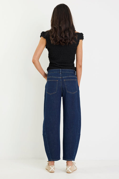 Person wearing blue jeans and a black top on a white background