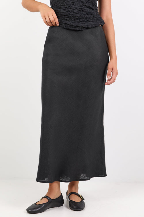 Person wearing a black off-shoulder top and long skirt on a white background
