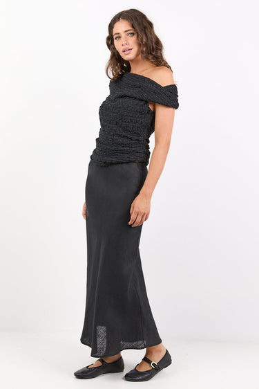 Person wearing a black off-shoulder top and long skirt on a white background