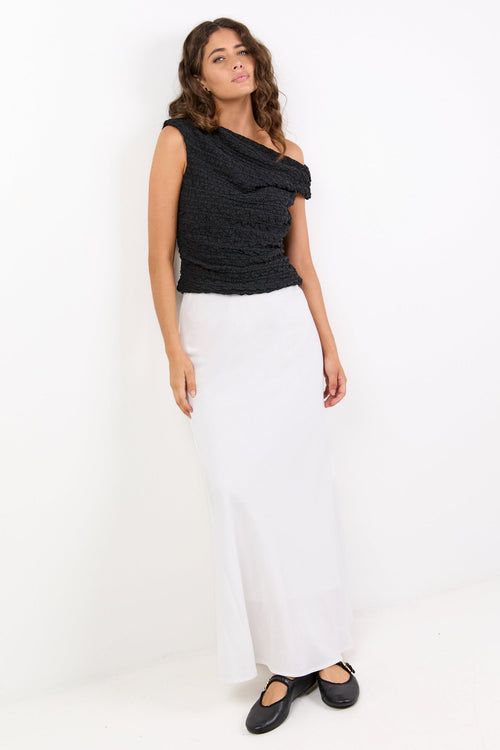 Woman wearing a black top and white skirt on a white background