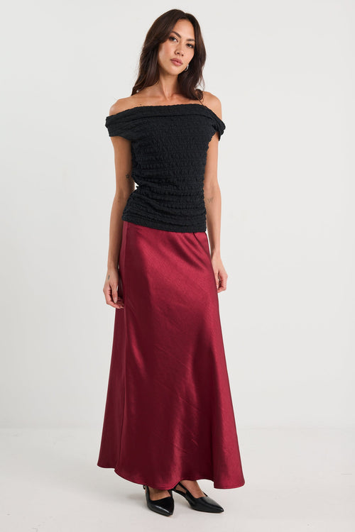 Woman wearing a black off-shoulder top and red skirt on a white background