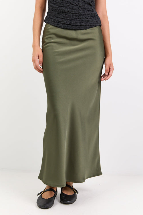 Woman wearing a black off-shoulder top and green skirt on a white background