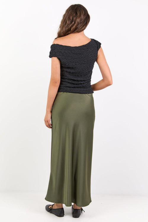 Woman wearing a black top and green skirt on a white background