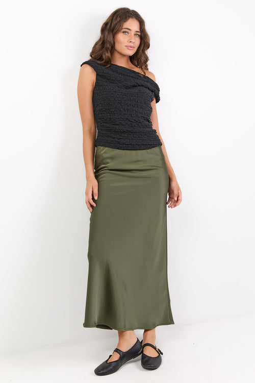 Woman wearing a black top and green skirt on a white background