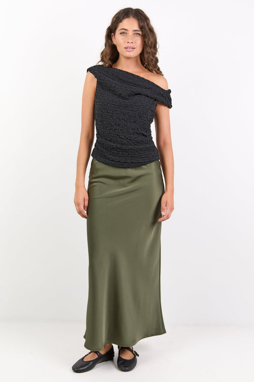 Woman wearing a black off-shoulder top and green skirt on a white background