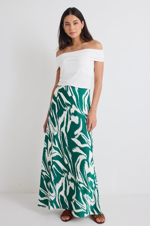 model wears off the shoulder white top and a green zebra print satin skirt