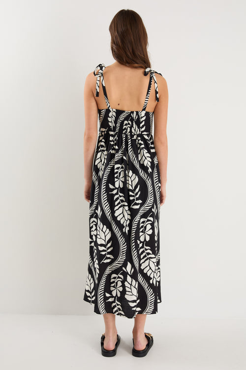 The model wears a black and white leaf print strappy maxi dress with black sandals