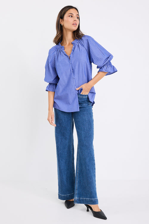 model wears a blue and white stripe shirt with dark blue jeans