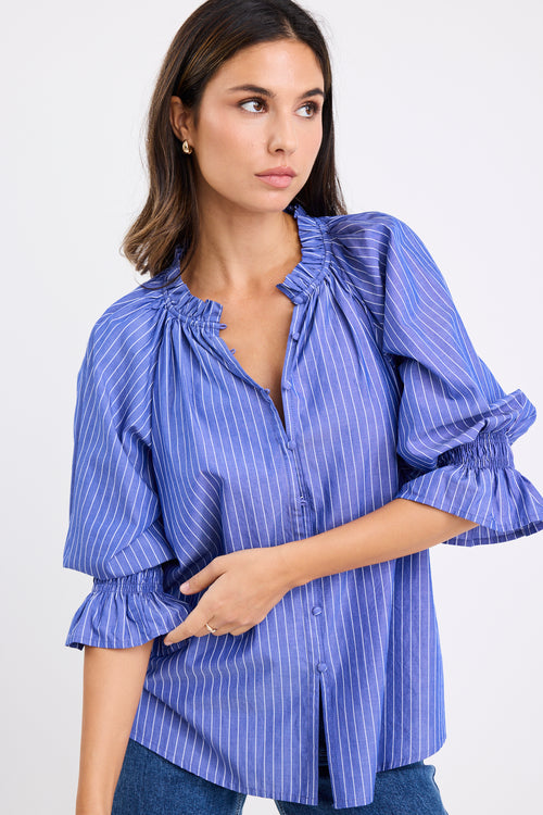 model wears a blue and white stripe shirt with dark blue jeans