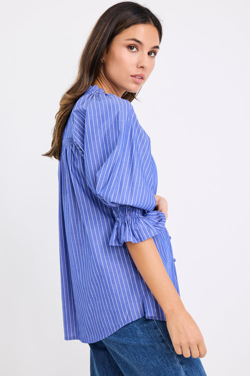 model wears a blue and white stripe shirt with dark blue jeans