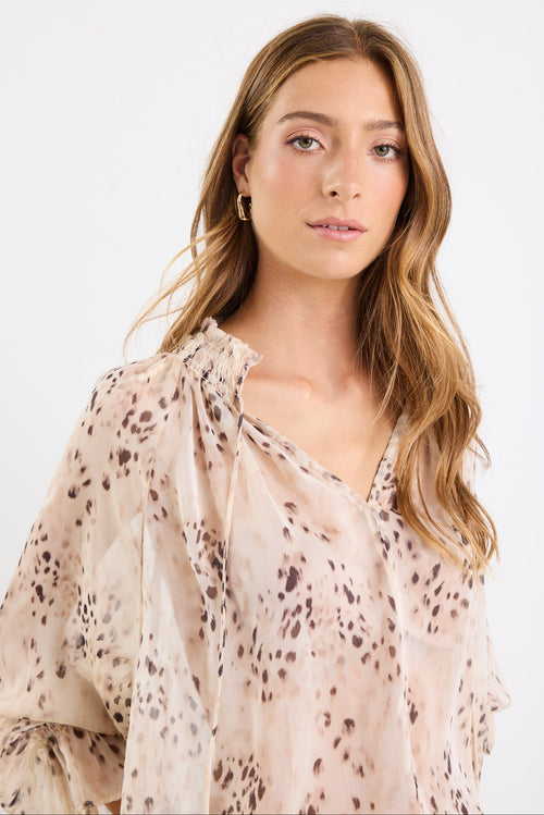 Woman wearing a beige blouse with a subtle pattern on a white background