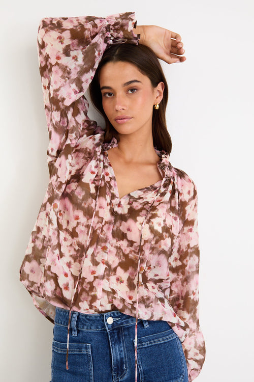 Woman wearing a floral blouse and jeans against a white background