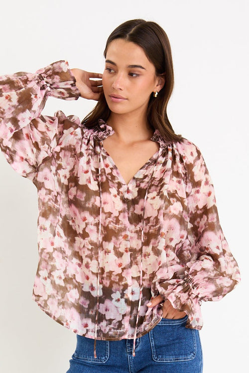 Woman wearing a floral blouse and blue jeans on a white background