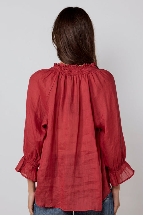 Person wearing a red blouse and blue jeans against a white background