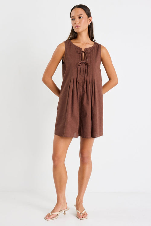 Woman wearing a brown mini dress with tie front and pleating