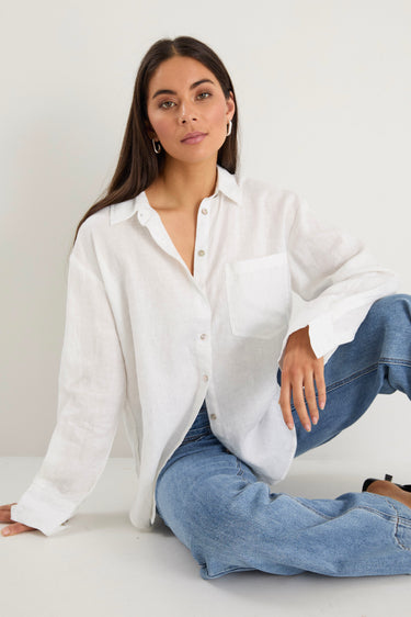 model wears a white linen shirt with blue jeans
