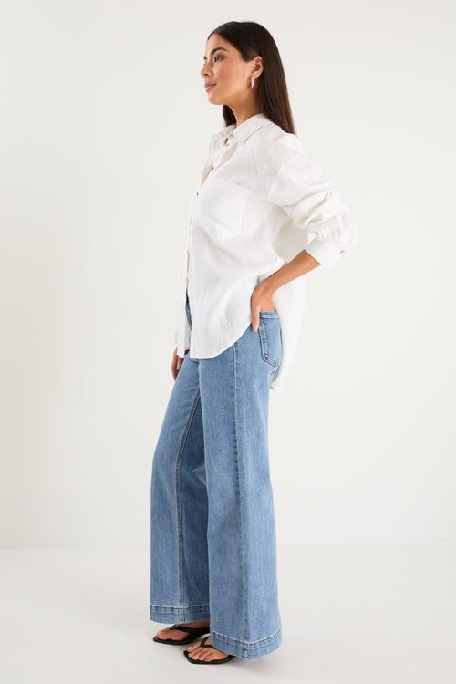 model wears a white linen shirt with blue jeans