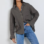 model wears a khaki stripe button up collared shirt with blue jeans