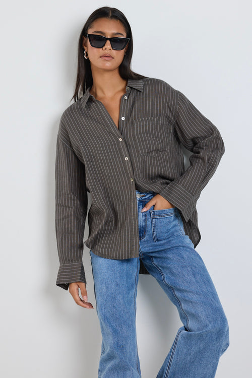 model wears a khaki stripe button up collared shirt with blue jeans