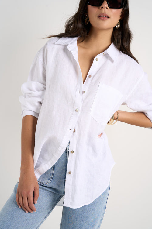 Model wears white linen shirt and light blue jeans