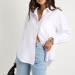 Model wears white linen shirt and light blue jeans