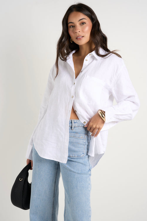 Model wears white linen shirt and light blue jeans