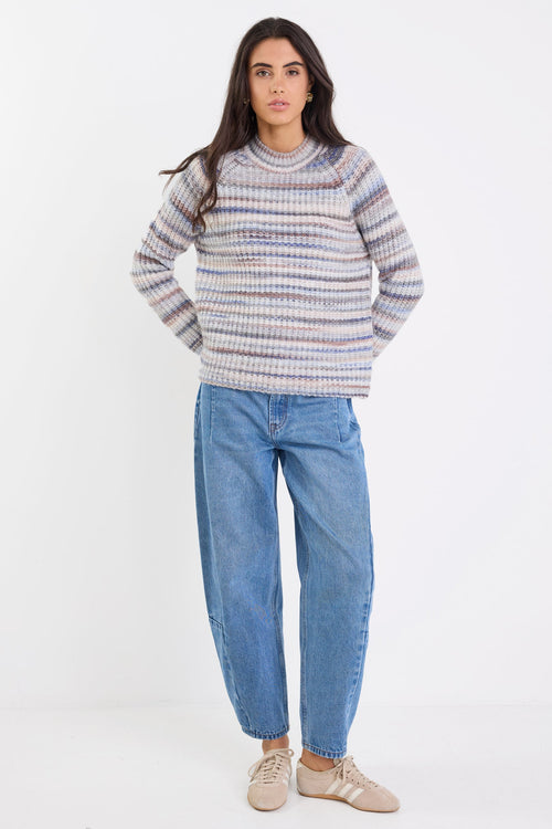 Woman wearing a striped sweater and blue jeans on a white background