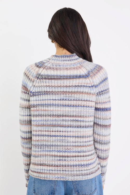 Person wearing a patterned sweater and jeans on a white background