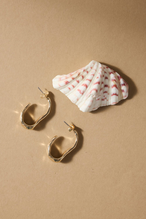 Gold hoop earrings with a seashell on a beige background