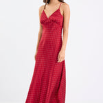 Woman wearing a red satin midi dress with white polka dots, adjustable spaghetti straps, and a bias-cut silhouette, standing against a white background.