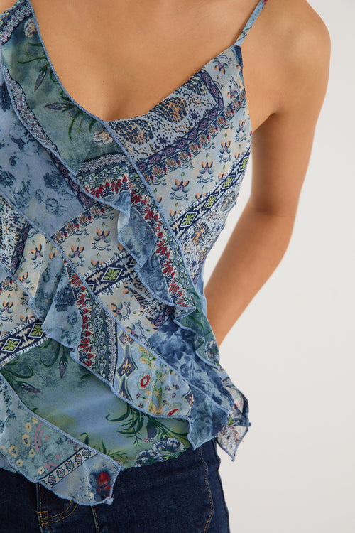 Woman wearing a strappy blue floral scarf-print top with ruffle detailing, styled with indigo jeans.