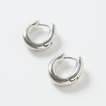 A pair of small oval-shaped wavy rhodium hoop earrings photographed on a clean white background.