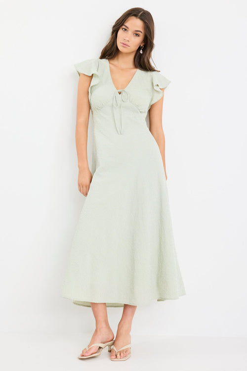 Woman wearing a sage green gingham midi dress with flutter sleeves and keyhole tie neckline.