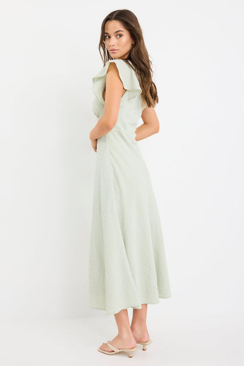 Woman wearing a sage green gingham midi dress with flutter sleeves and keyhole tie neckline.