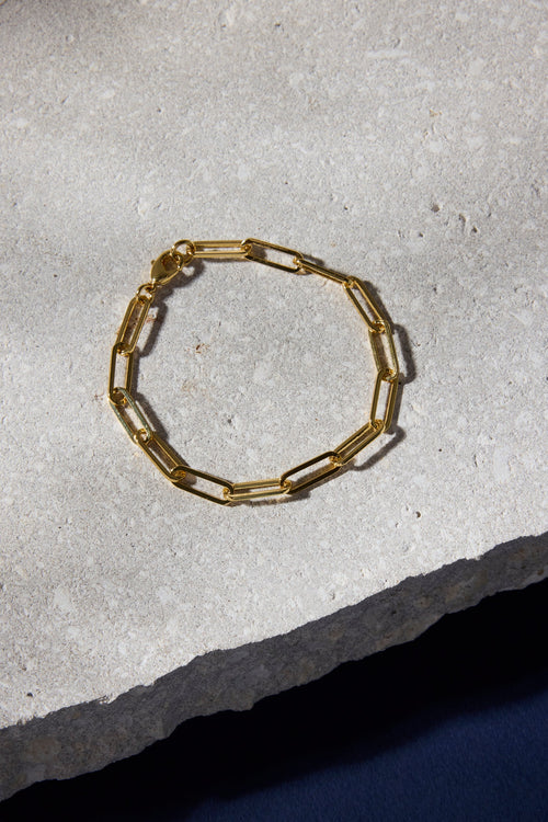 Gold chain bracelet on a textured stone surface