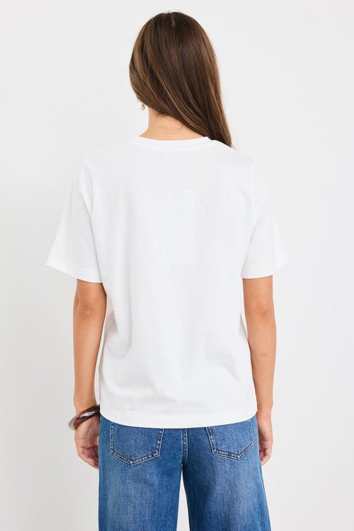 The model wears a white t-shirt with red graphic text and blue jeans