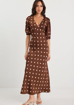Woman wearing a brown polka dot dress on a white background