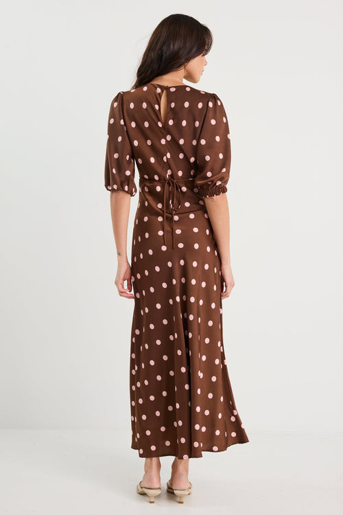 Woman wearing a brown polka dot dress on a white background