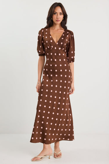 Woman wearing a brown polka dot dress on a white background