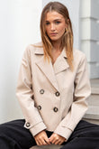 Woman wearing a beige coat sitting on steps outdoors
