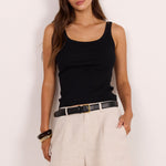 Woman wears black tank and cream coloured linen shorts.