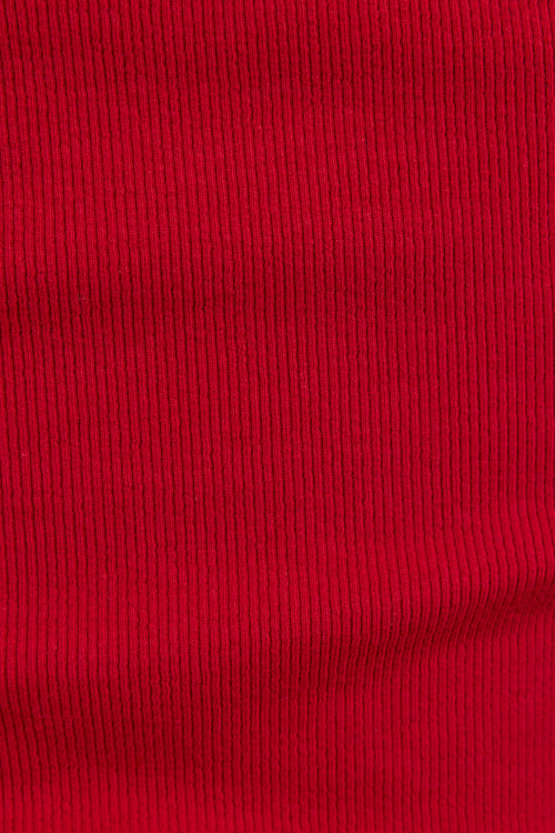 A close-up of a bright red ribbed knit fabric texture, showing the vertical ribbing pattern and material detail.