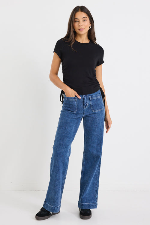 model wears a black cropped tee with blue jeans