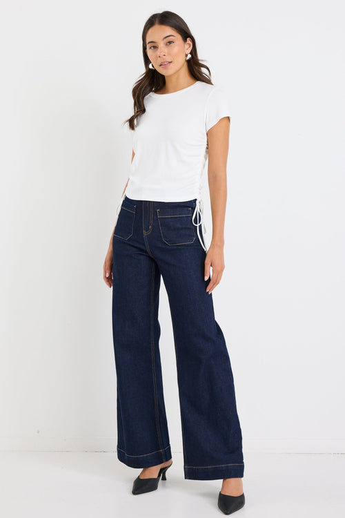 Model wears a white top with blue jeans