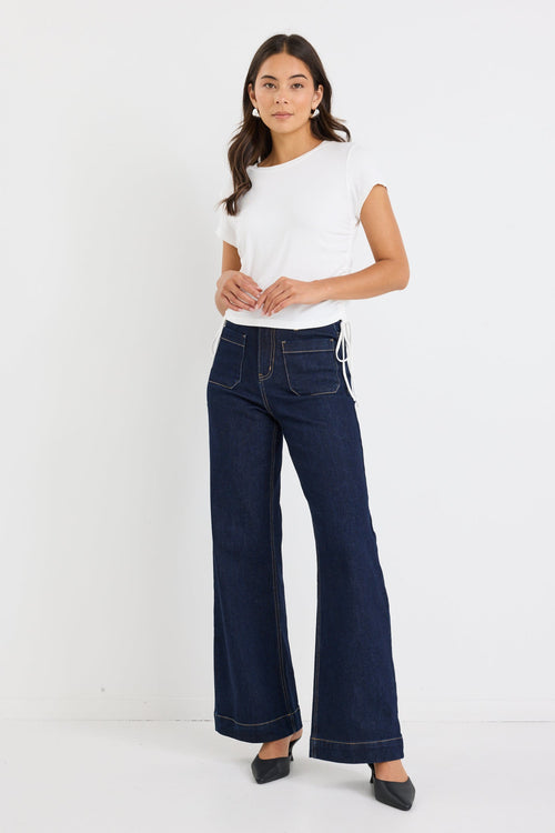 Woman wearing a white top and dark blue jeans on a white background