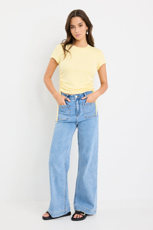 Woman wearing a yellow t-shirt and blue jeans on a white background