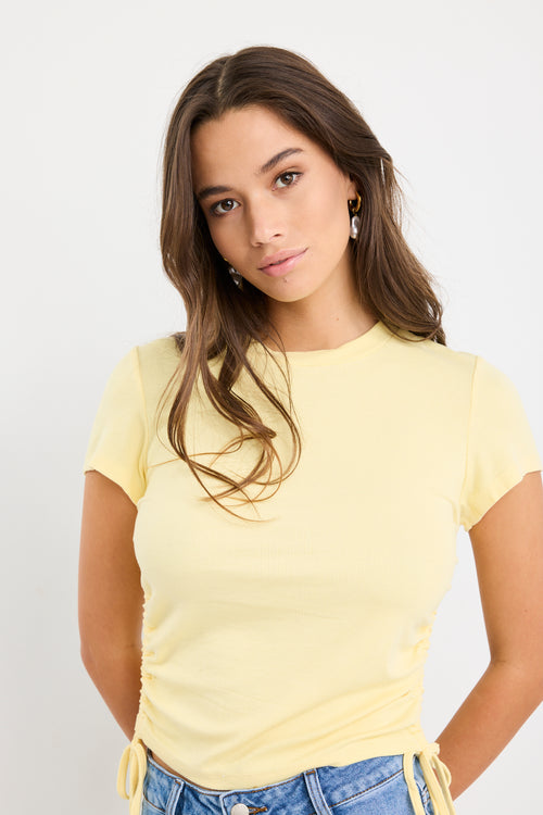 Woman wearing a yellow t-shirt against a plain background
